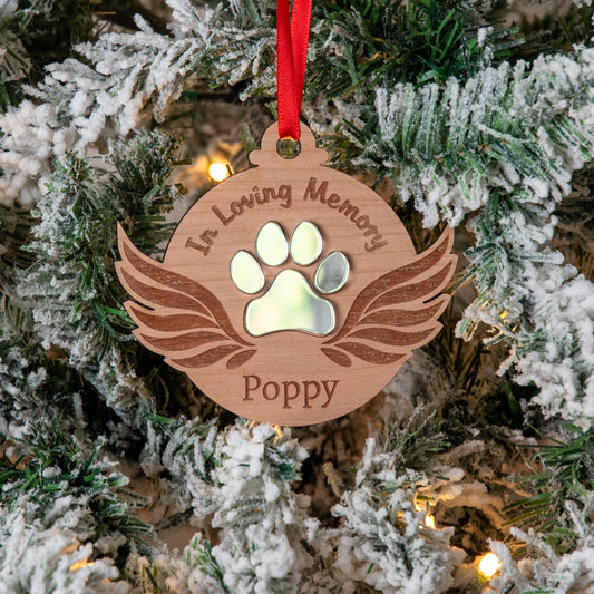 Memorial ornament with paw print and 'In Loving Memory' text on a Christmas tree.