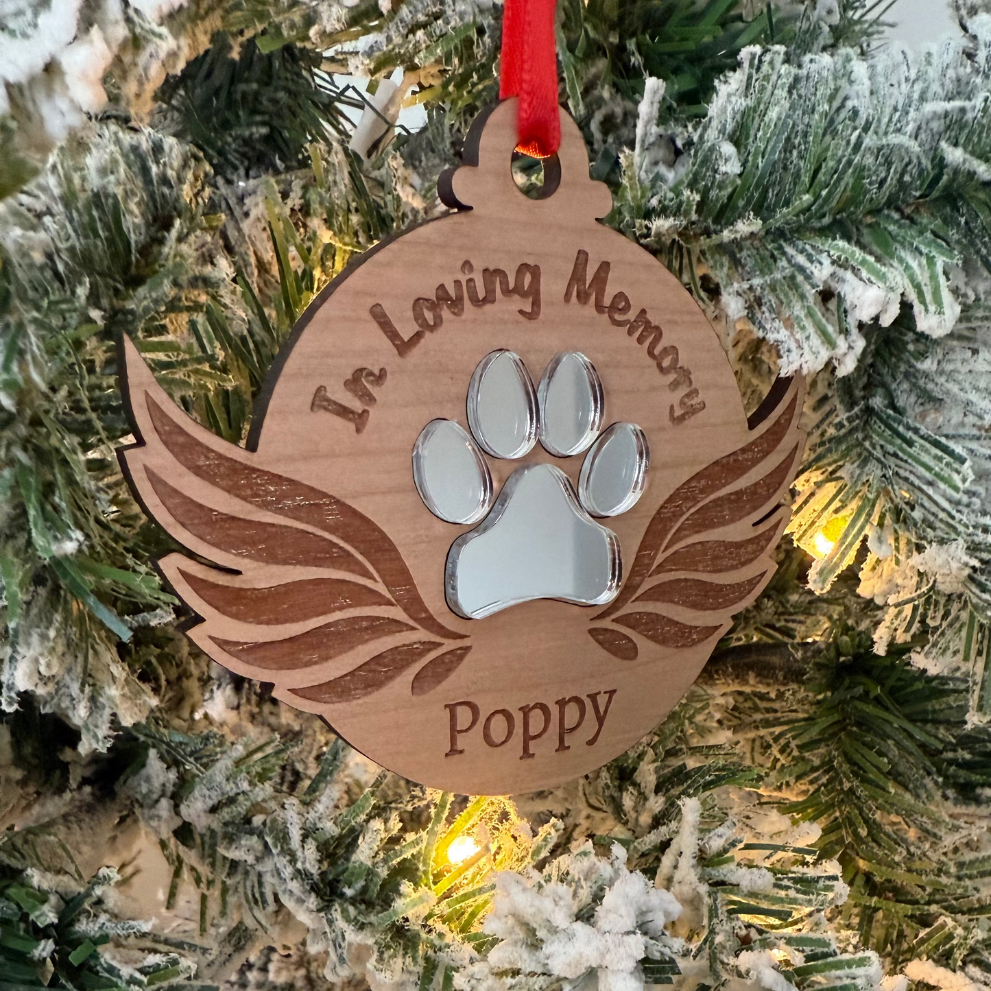 Ornament with paw print and 'In Loving Memory Poppy' text on a Christmas tree.