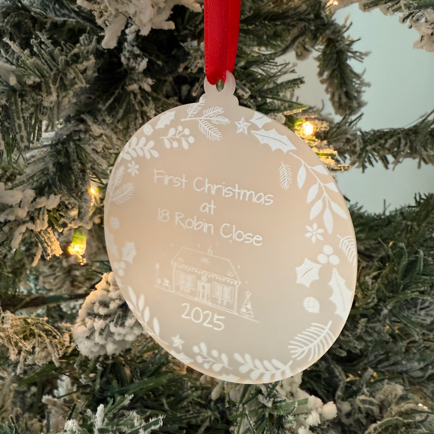 Decorative Christmas ornament on a tree with text and a red ribbon.